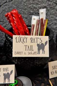 a table topped with lots of different types of candies and candy bar signs next to cupcakes