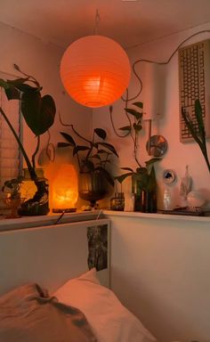 a room filled with lots of plants next to a light hanging from the ceiling over a bed