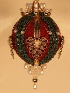 a red ornament hanging from the ceiling with beads and chains on it's sides