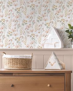 a wooden dresser topped with a basket next to a wallpaper