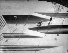 two people are walking in the shadows of benches