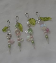 five charms with leaves and beads hanging from them on a white surface, one has a star in the middle