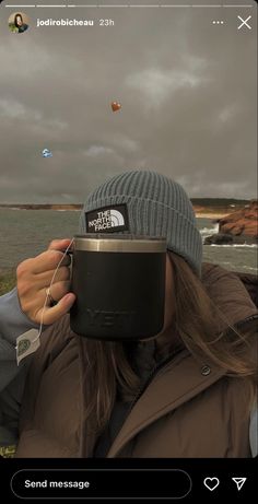 a woman taking a photo with her cell phone while wearing a beanie and jacket