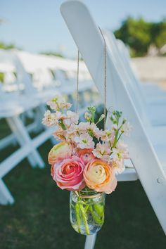 a vase filled with flowers sitting on top of a white chair next to lawn chairs