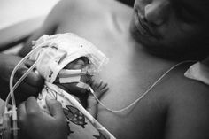 a black and white photo of a person holding a baby in a hospital bed with an iv attached to it