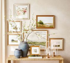 a table with vases and pictures on the wall