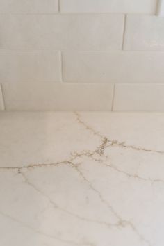 a marble counter top in a bathroom with white tile and gray grouting on it