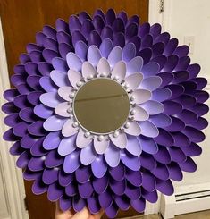 a person holding up a purple flower shaped mirror