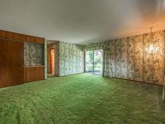 an empty living room with green carpet and wallpaper