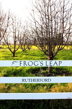 there is a sign that says frog's leap in front of some grass and trees