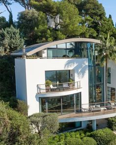 an aerial view of a modern house with trees in the foreground and palm trees on the other side