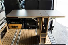 the interior of an rv with wood flooring and black leather seats, including a dining table