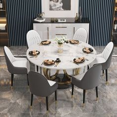 a dining room table with white chairs and gold accents