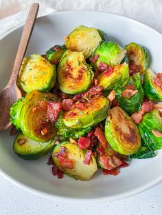 brussel sprouts with bacon in a white bowl next to a wooden spoon