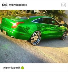 a green car is parked on the side of the road