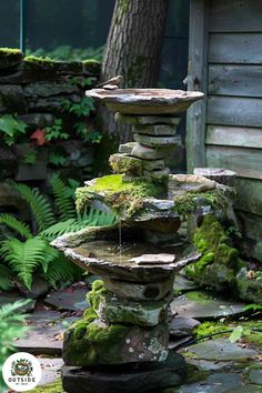 a stone fountain with moss growing on it in the middle of a garden next to a house