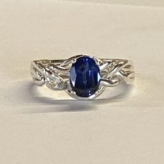 This is a ladies' puzzle ring set with a faceted, oval synthetic sapphire.   The bands are made of solid .925 sterling silver or 10k, 14k, or 18k gold or platinum.  While the sterling silver rings come only in the natural silver color, the gold rings can be made in either natural yellow gold, white gold, rose gold or green gold.  (Green gold can only be 14k or 18k.) The ring still comes apart and is easy to assemble with our instructions. We can make it in any ring size. Additionally we have a m Adjustable Oval Sapphire Ring In Sterling Silver, Sterling Silver Sapphire Ring For Anniversary, Oval Cabochon, Oval Sapphire Ring In Sterling Silver, Oval Sapphire Solitaire Jewelry, Oval Sapphire Ring With Center Stone In Sterling Silver, Adjustable Oval Sapphire Ring, Oval Sapphire Ring Hallmarked, Oval Sapphire Rings With Polished Finish, Oval Silver Sapphire Ring With Polished Finish