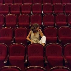 a woman sitting in the middle of an empty auditorium