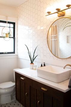 a bathroom with a toilet, sink and mirror in it's corner area next to a window