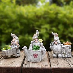 three garden gnomes sitting on top of wooden boards