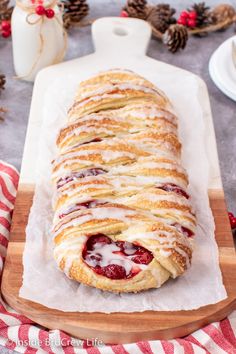 a pastry with icing and strawberries is on a cutting board