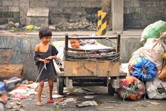 two young boys standing next to a pile of garbage