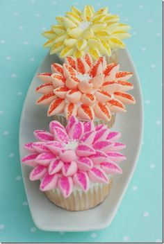 three cupcakes decorated with flowers on a plate