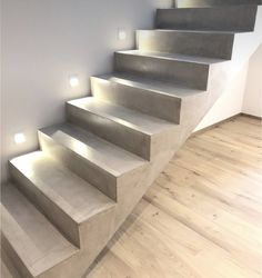 a set of concrete stairs with lights on the side and in between them is a white wall