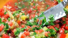 a yellow bowl filled with chopped vegetables and a large knife on top of the bowl