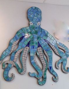 an octopus made out of blue and green tiles on the wall in front of a light fixture