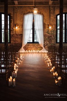 the aisle is lined with candles and drapes for an elegant wedding ceremony at anchor & veil