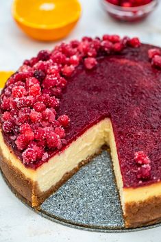 a cheesecake topped with raspberries on top of a plate next to oranges