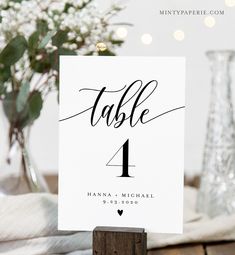 a table number card with the word table 1 printed on it, next to a vase filled with baby's breath flowers