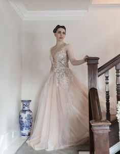 a woman in a wedding dress standing on the stairs next to a vase with flowers