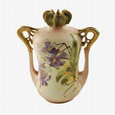 a white vase with flowers painted on it's sides and gold trimmings