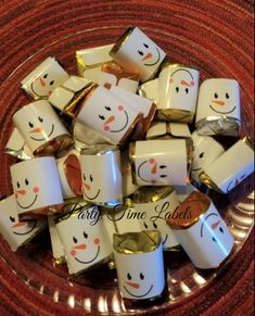 a plate full of candy wrapped in gold and white paper with smiling faces on them