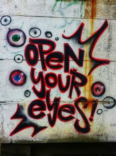 graffiti on the side of a building that says open your eyes