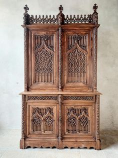 an old wooden cabinet with intricate carvings on the front and back doors, sitting against a wall