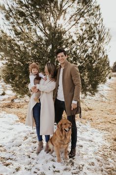 a man, woman and child are standing in the snow with a large brown dog