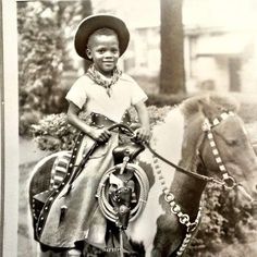 an old black and white photo of a young boy on a horse