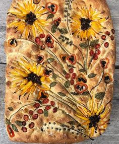 a pizza with sunflowers and cherries on it sitting on top of a wooden table