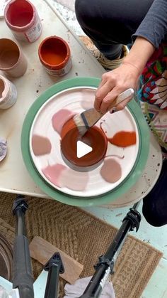 a woman is painting on a plate with paint