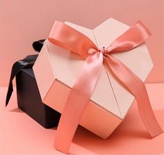 an open gift box with a pink ribbon tied around it and a black bow on top