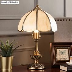 a table lamp sitting on top of a wooden desk next to a potted plant