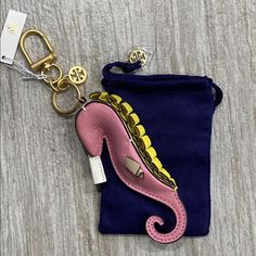 a cell phone case with a pink and yellow sea horse keychain attached to it