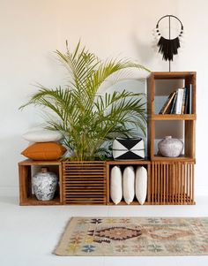 a wooden shelf filled with lots of books and vases on top of a rug