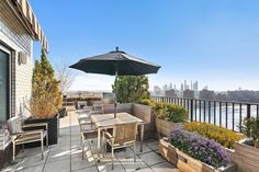 an outdoor table and chairs on a patio overlooking the water with buildings in the background