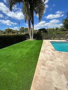 an empty pool in the middle of a lush green lawn next to a palm tree