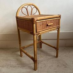 a wicker desk with a drawer on the top and bottom, against a white wall