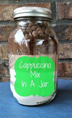 a jar filled with chocolate chips sitting on top of a blue table cloth next to a brick wall